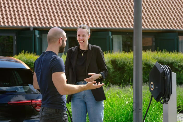 Zwei Personen unterhalten sich vor einem ladenden Elektrofahrzeug